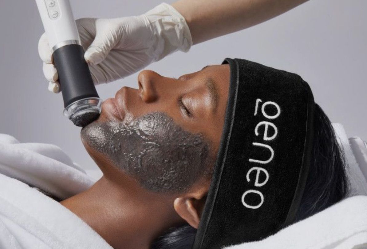 A woman is getting a facial treatment with a brush on her face.