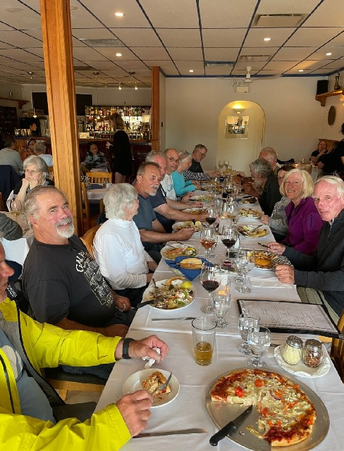 A group of people are sitting at a long table eating food