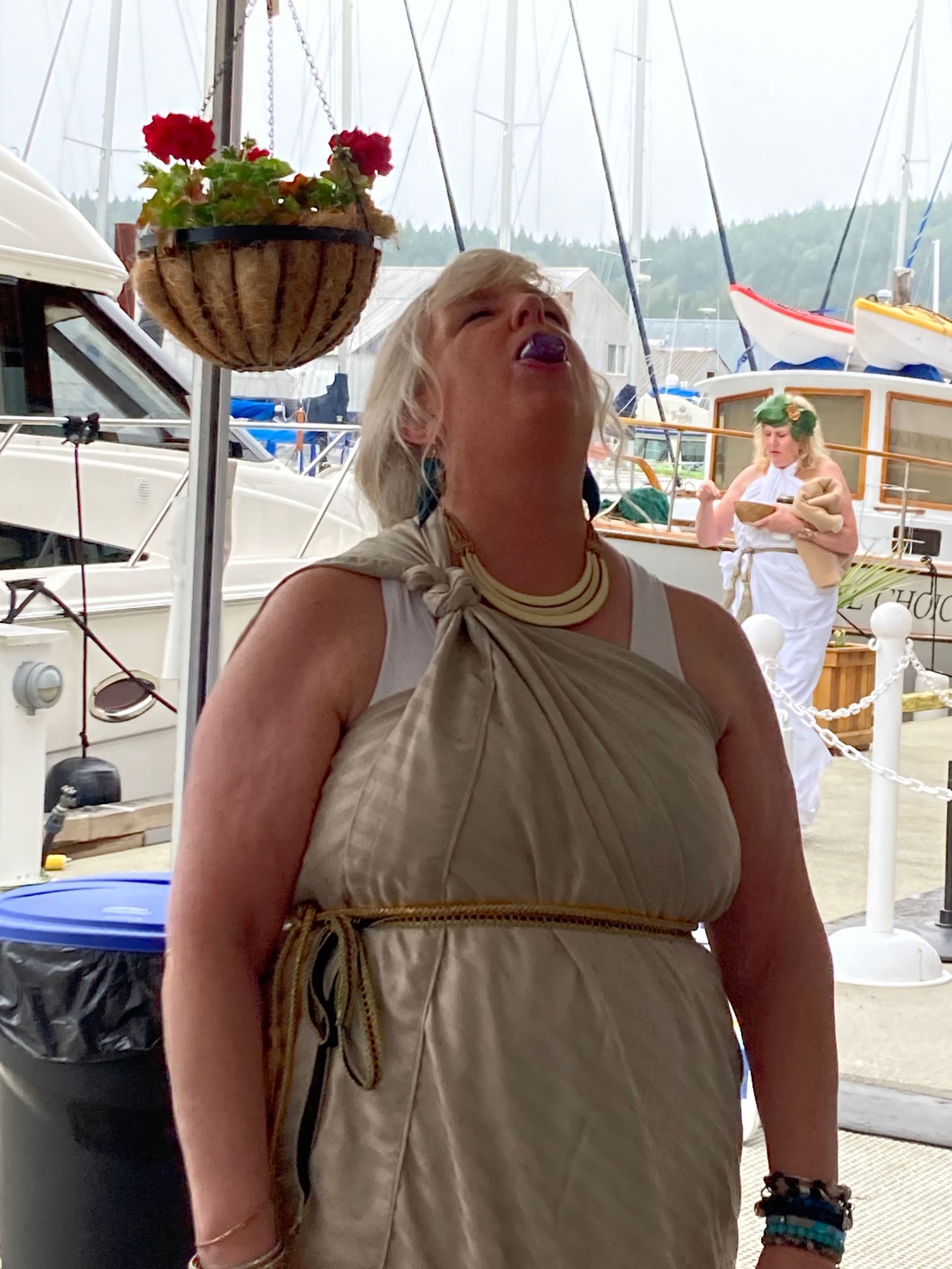 A woman in a tan dress is standing in front of boats