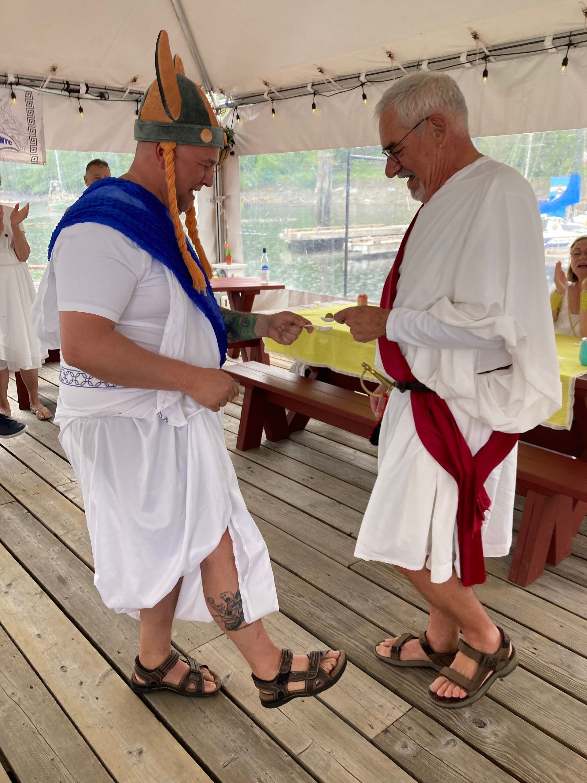 Two men dressed as romans are dancing on a wooden deck