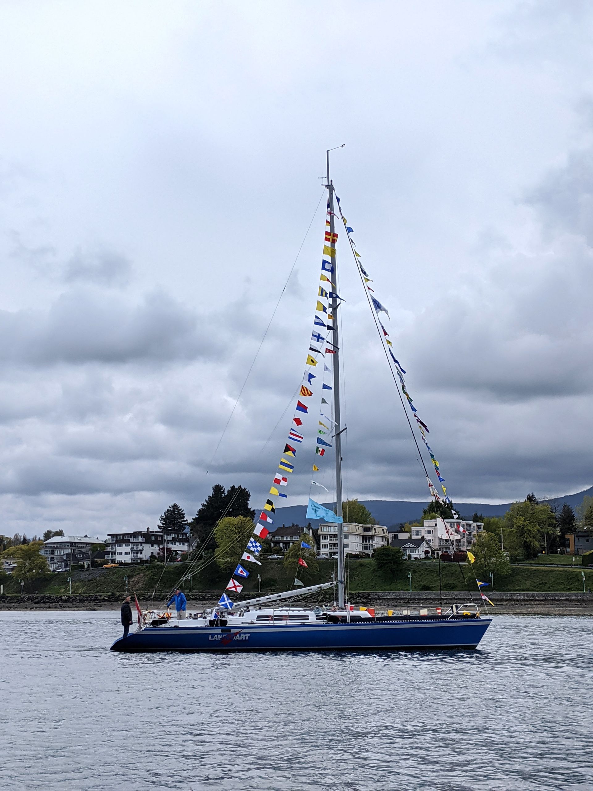 A sailboat with many flags on the mast is in the water