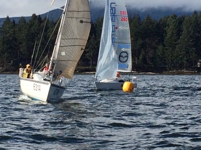 Two sailboats are racing on a lake and one of them has the word usa on the sail
