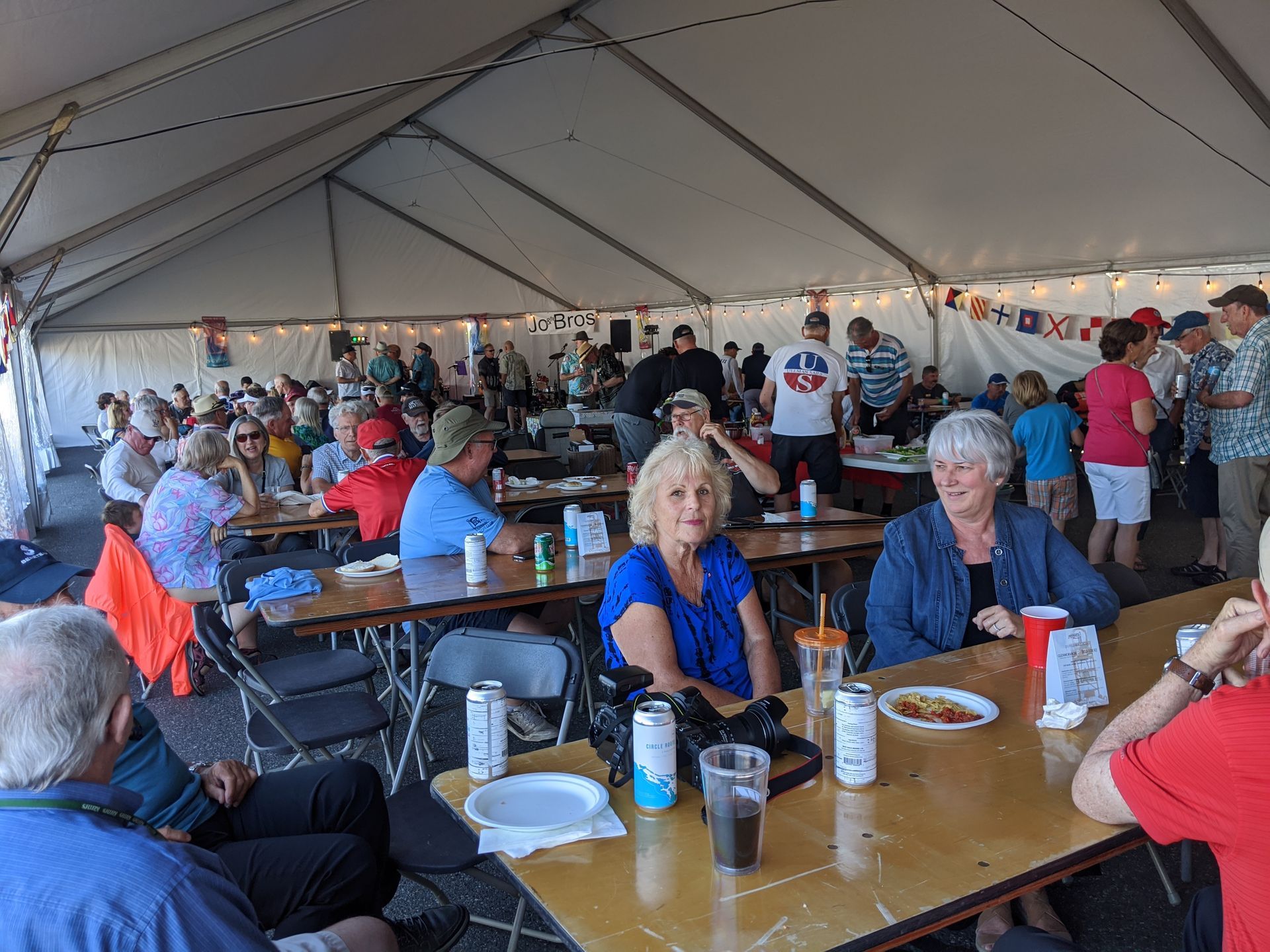 A group of people are sitting at tables under a tent.