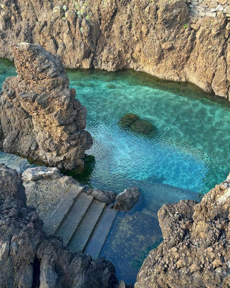 Rocky coastline with clear turquoise water and stone steps.