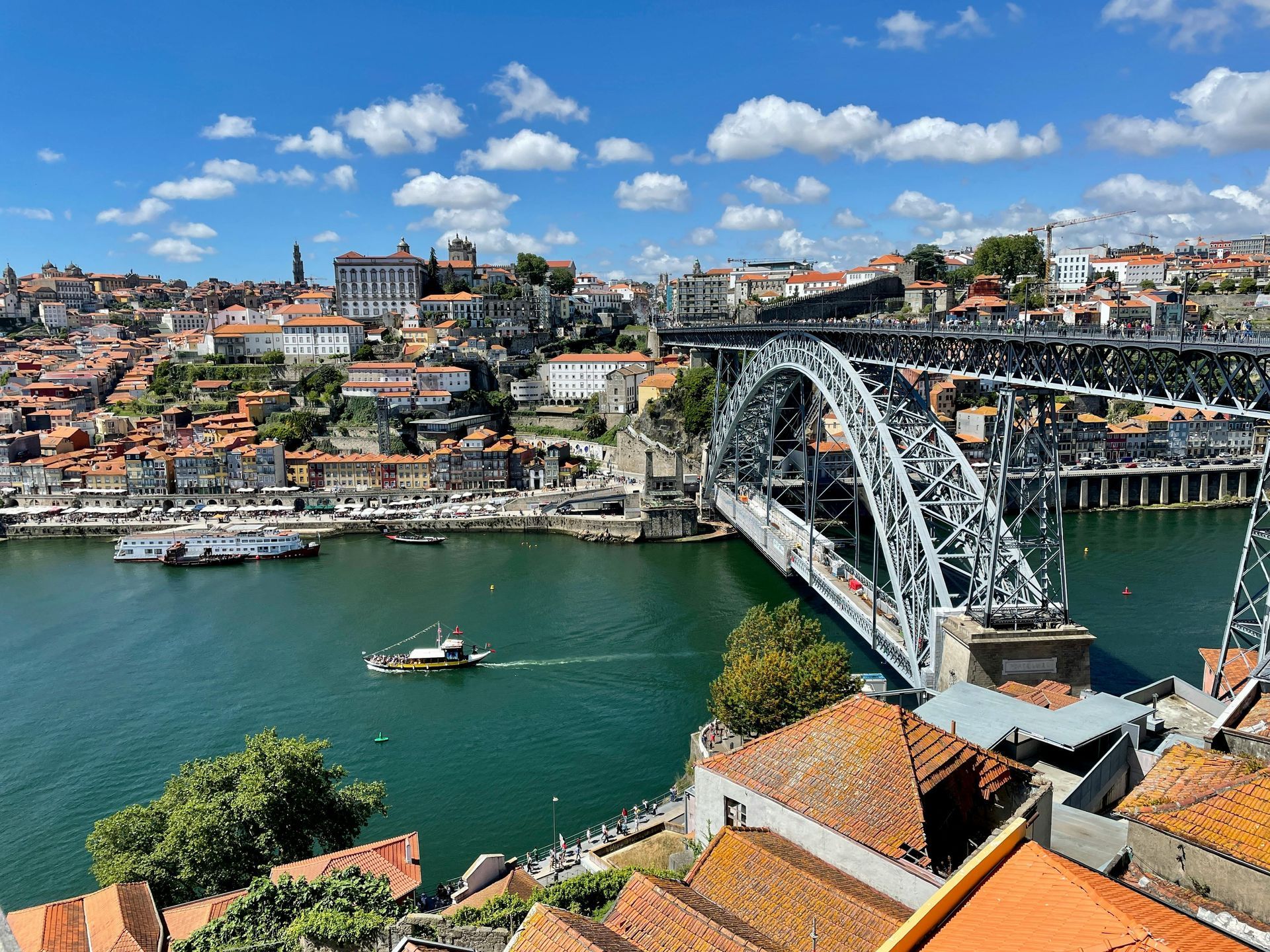 Cityscape of Porto, Portugal, with the Dom Luís I Bridge over the Douro River on a sunny day.