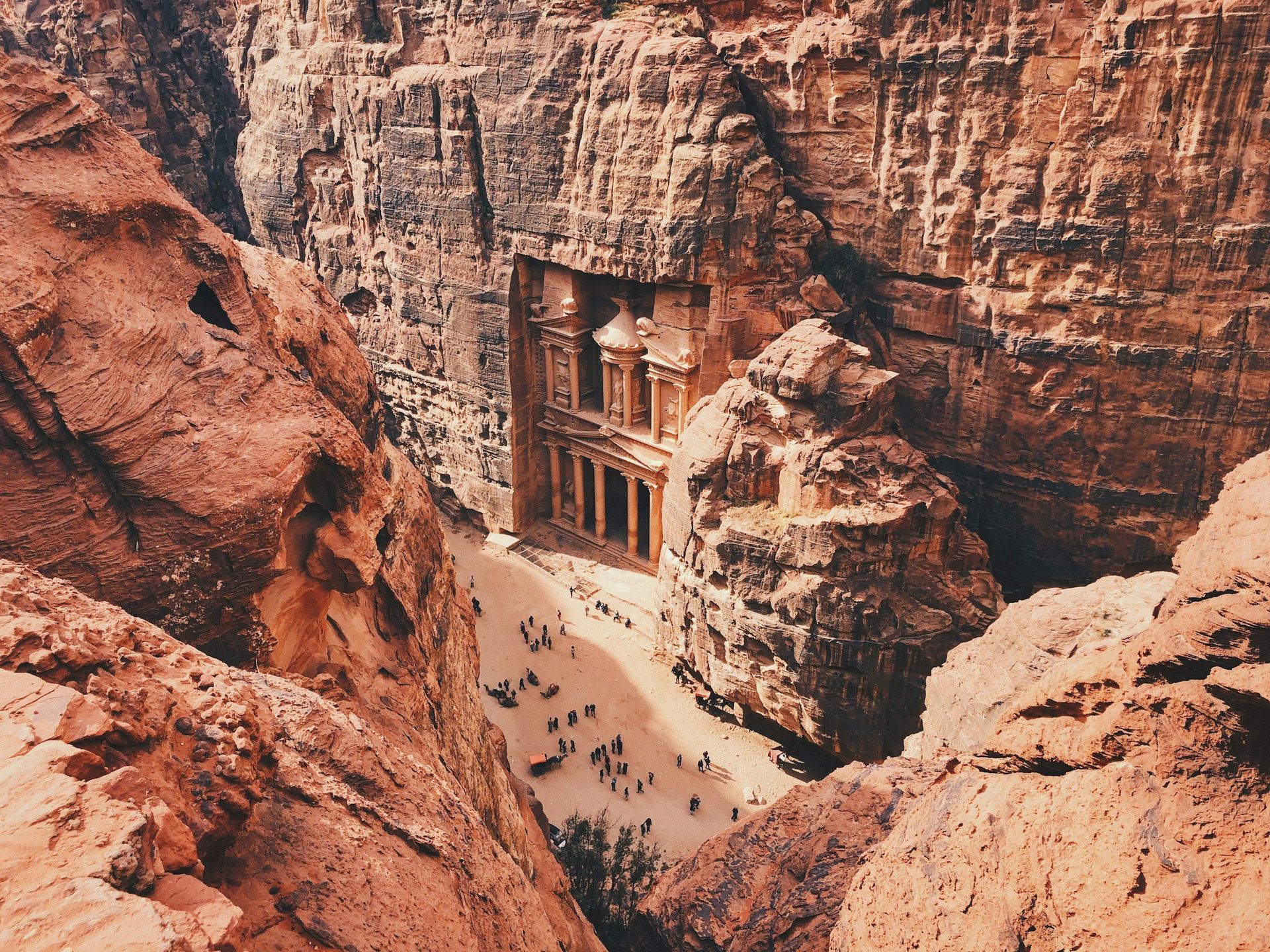 Petra, Jordan: Ancient rock-cut temple facade at the end of a narrow canyon, with tourists below.
