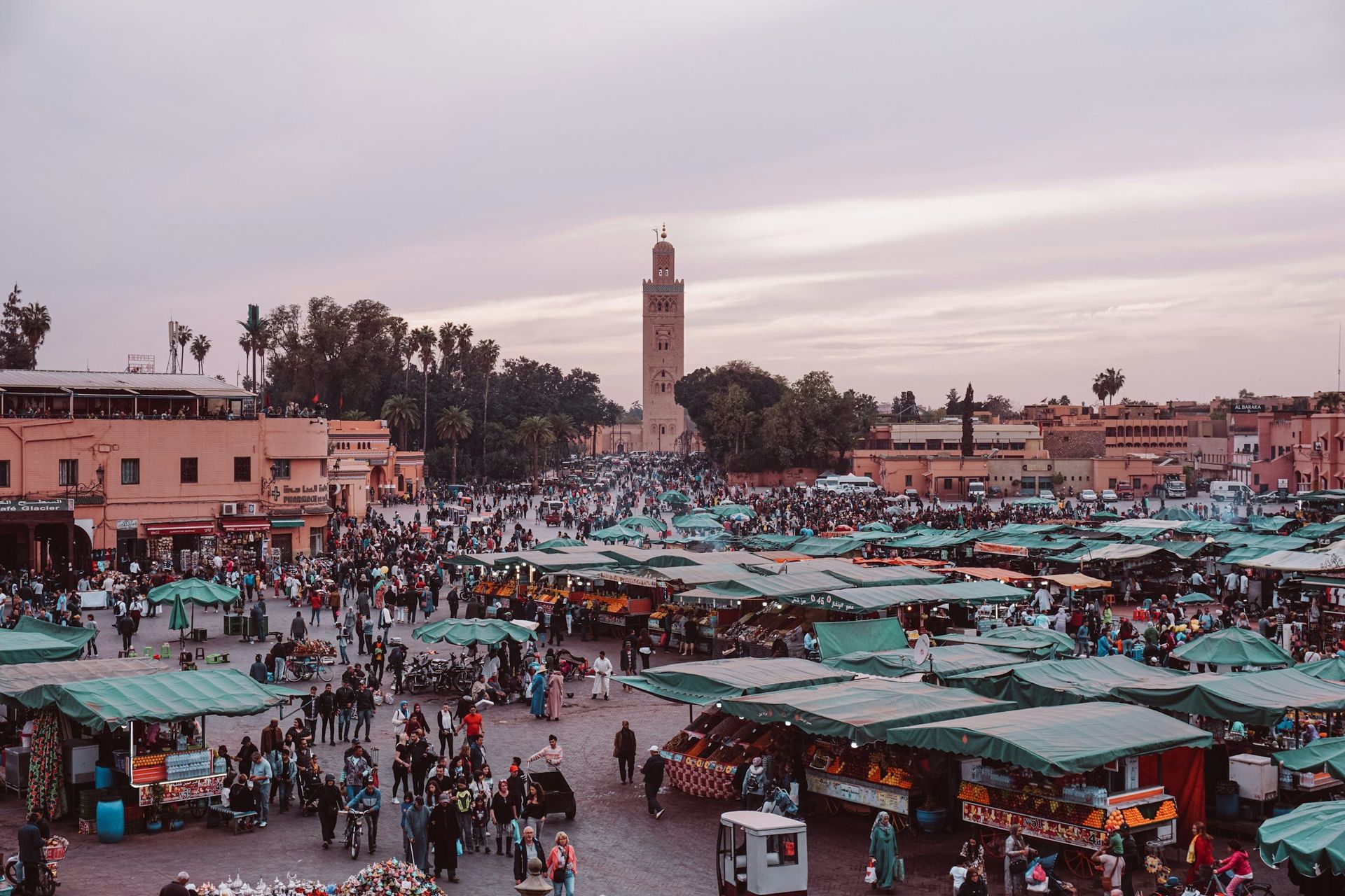 Jemaa el-Fna square in Marrakesh, Morocco, filled with vendors and people; Koutoubia Mosque visible in the background.