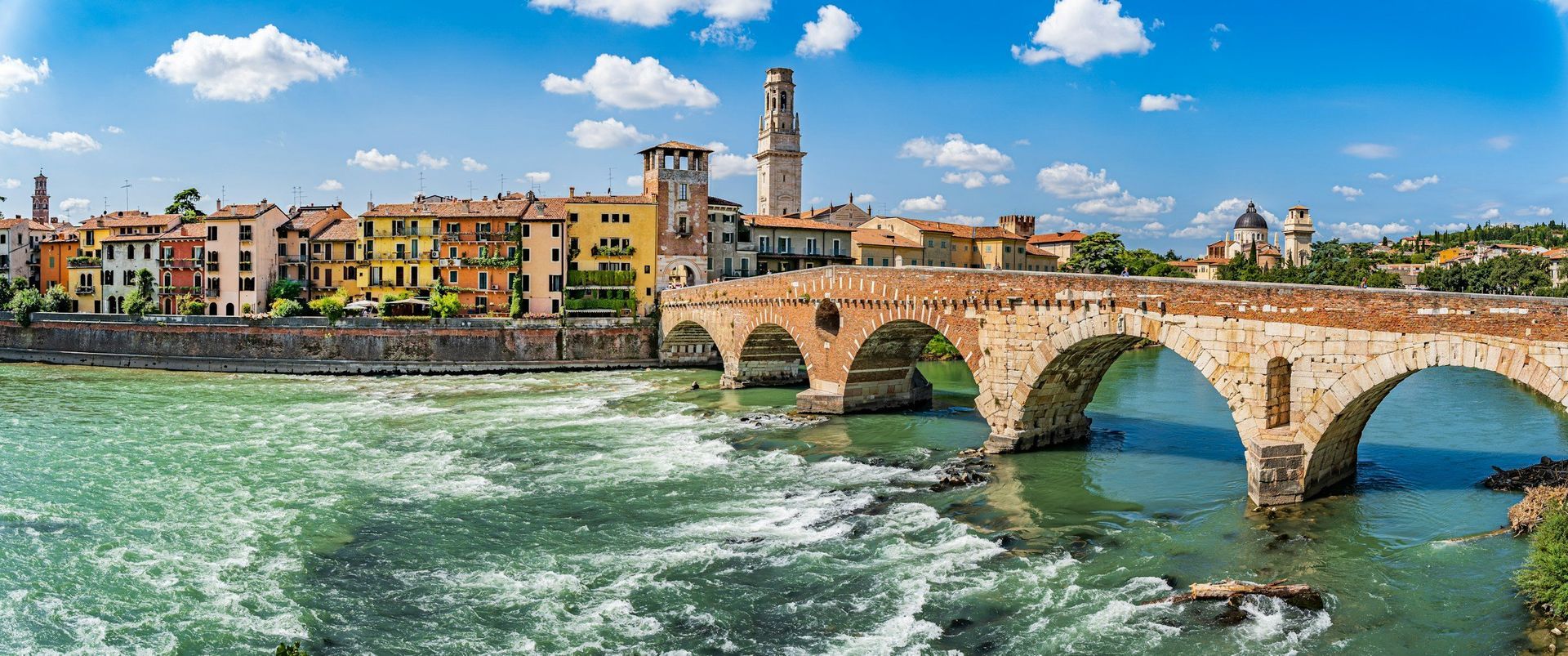 Verona cityscape with a bridge over a river on a sunny day.