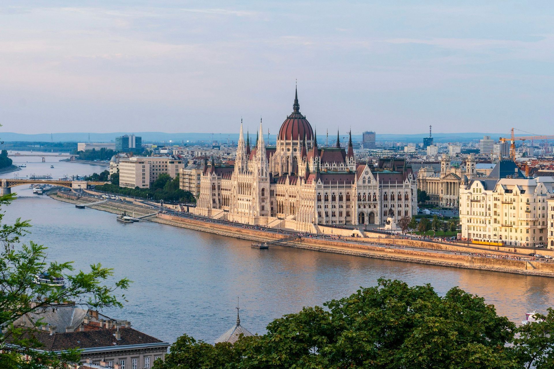 Hungarian Parliament building on the Danube River in Budapest, with city skyline in the background.