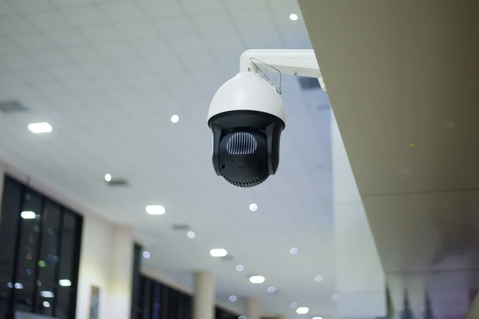 A security camera is hanging from the ceiling of a building.