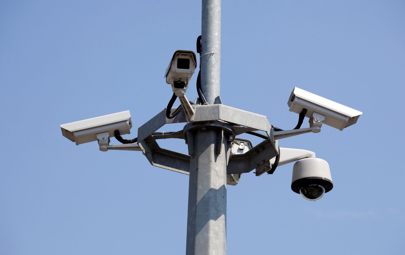 Three security cameras are sitting on top of a pole.