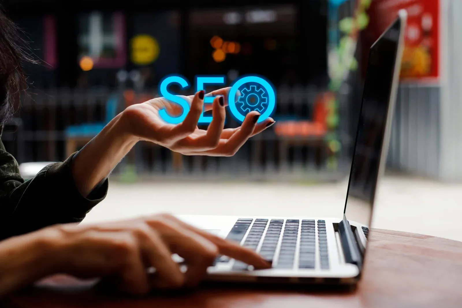 A woman is typing on a laptop computer while holding up her hand.