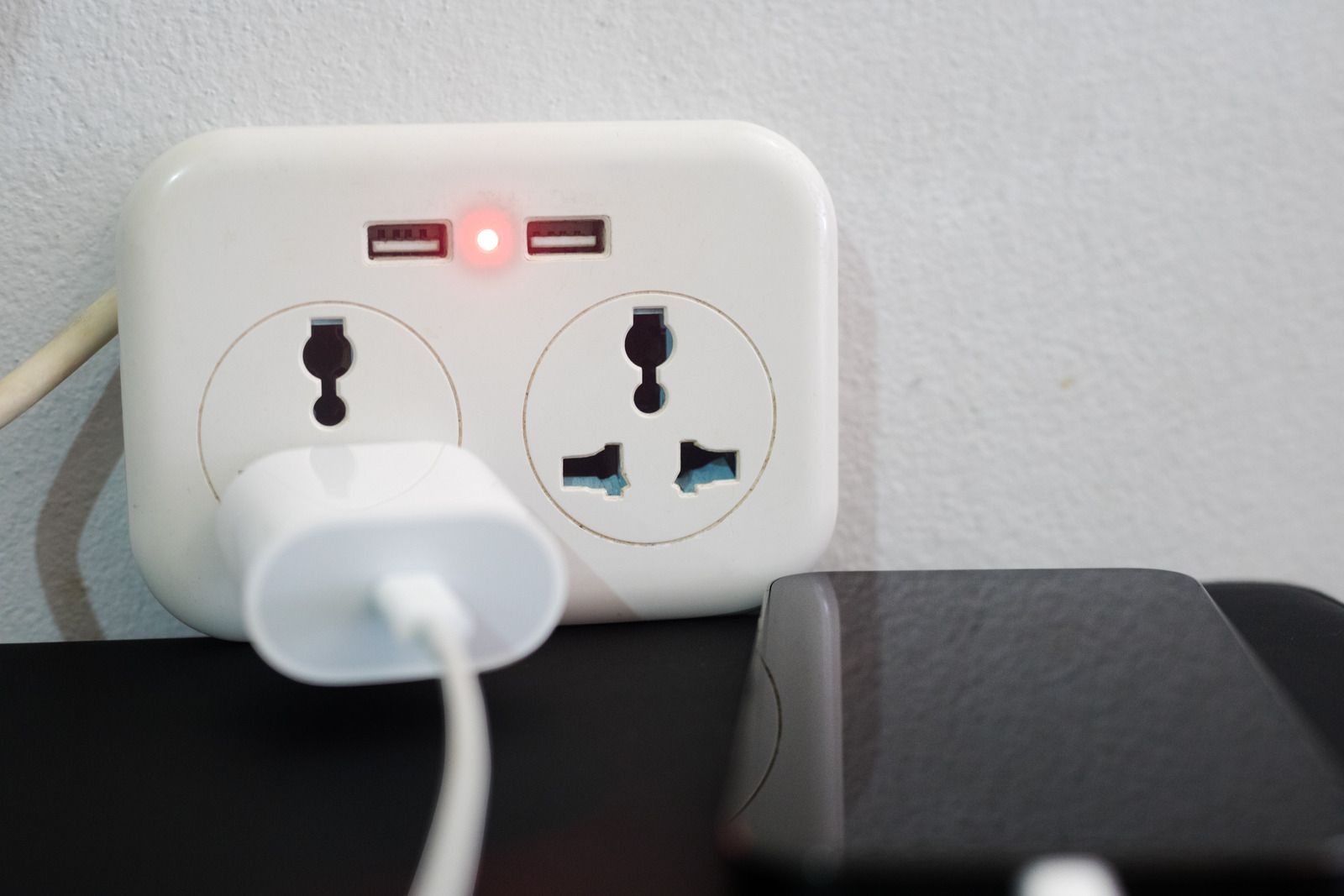 A white charger is plugged into a wall socket.