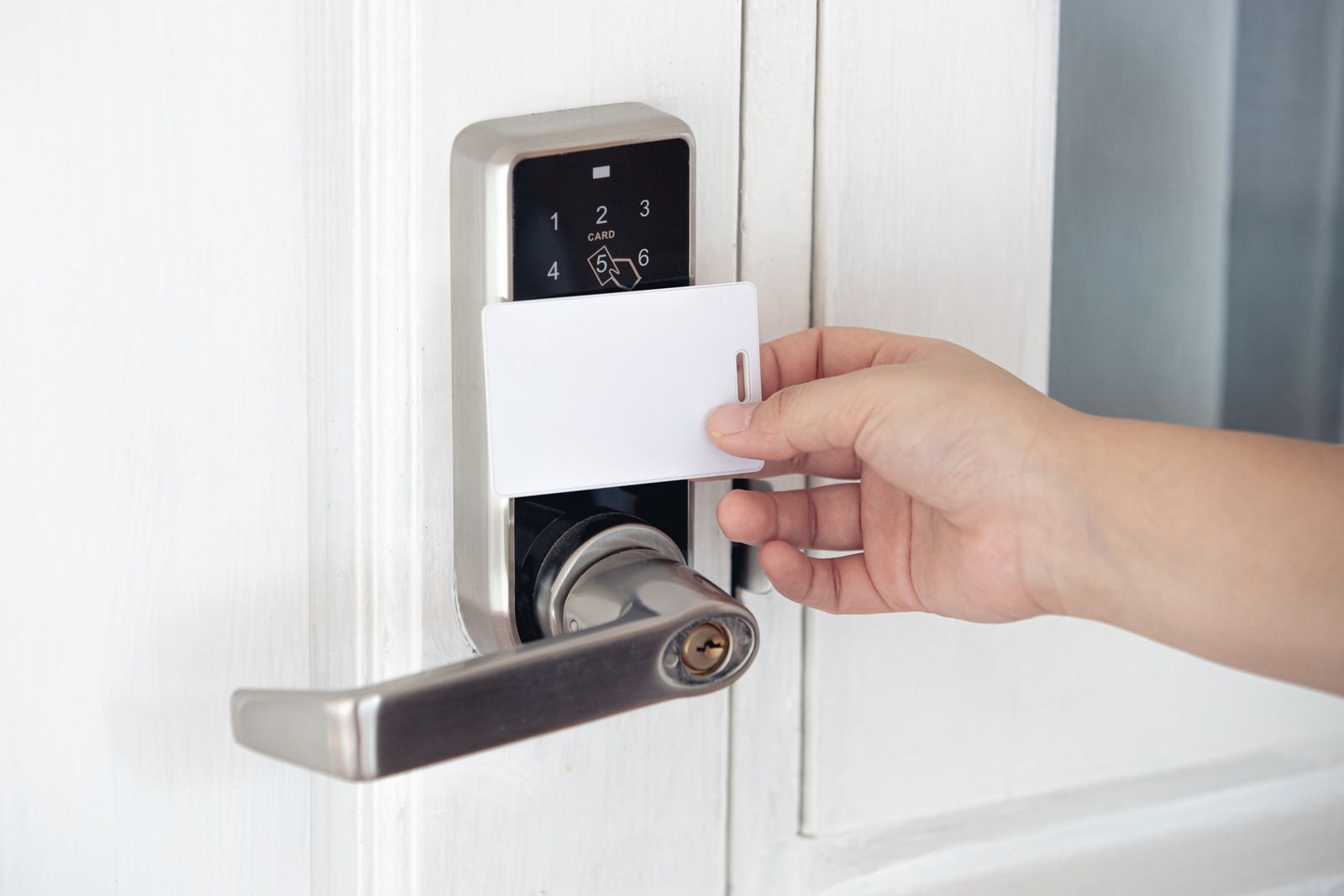 A person is inserting a credit card into a door lock.
