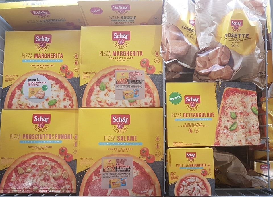 Vetrina freezer con scatole per pizza e prodotti da forno Schär, confezione gialla.