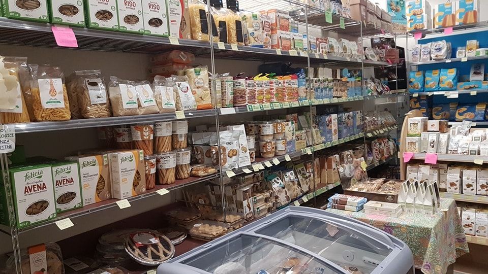 Scaffali pieni di prodotti alimentari confezionati nel corridoio di un supermercato, tra cui pasta, cracker e snack.