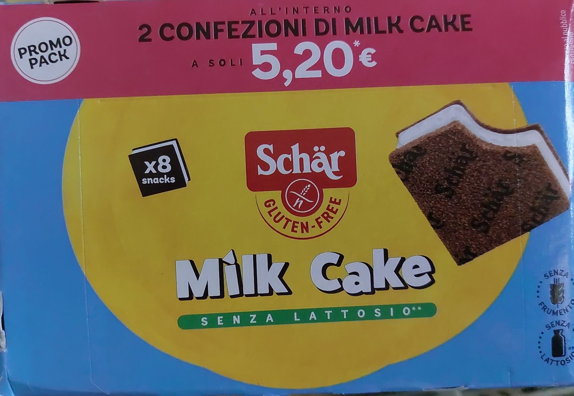 Scatola di torta al latte Schär, senza glutine, senza lattosio, confezione promozionale, con sfondo giallo e blu.