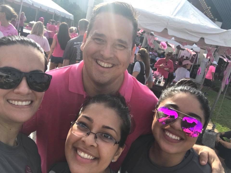 A group of people wearing pink sunglasses are posing for a picture.