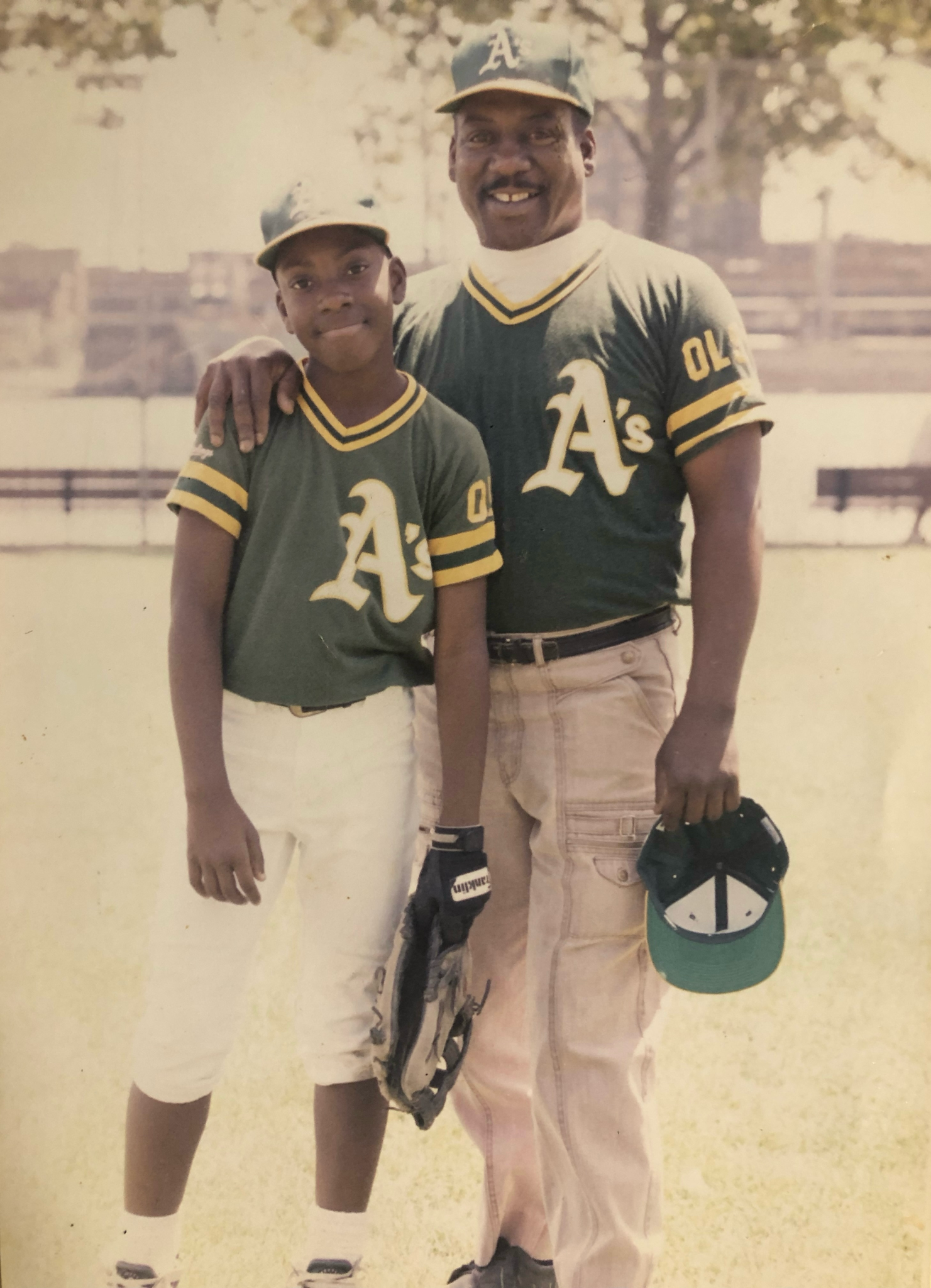 A man and a boy wearing a's jerseys pose for a picture
