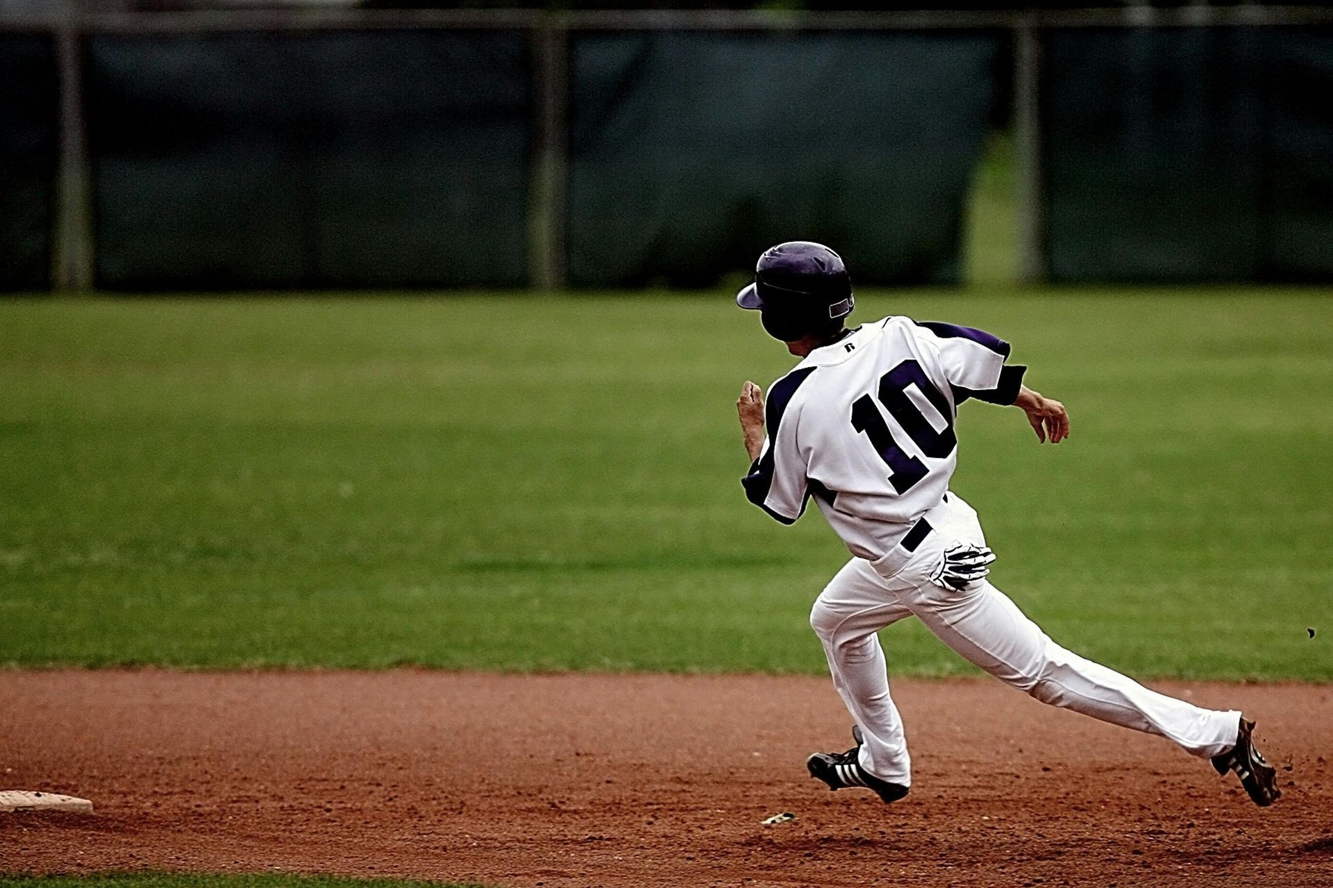 A baseball player with the number 10 on his back is running on the field.