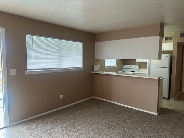 Beige living area with sliding glass door, kitchen bar, and window with blinds.