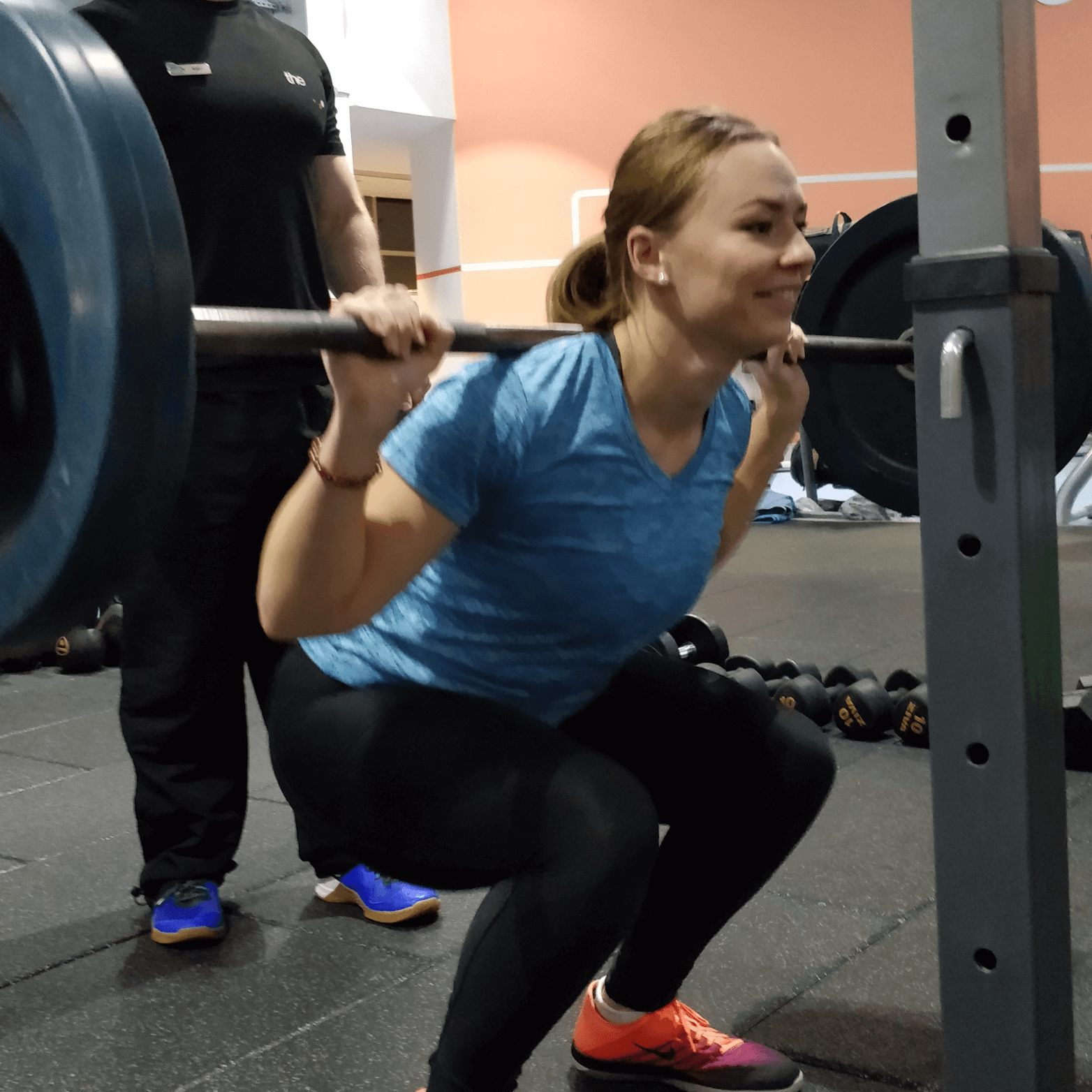 Happy client squatting with personal trainer in Glasgow