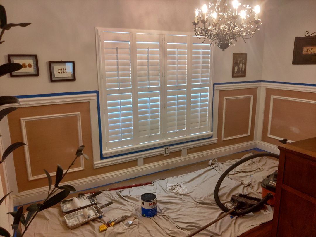A room is being painted with shutters and a chandelier
