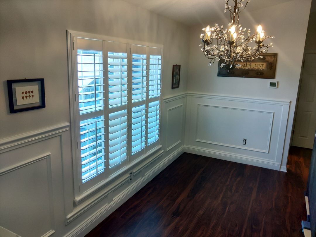A dining room with shutters and a chandelier