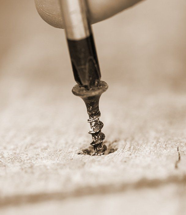 A person is screwing a screw into a piece of wood.