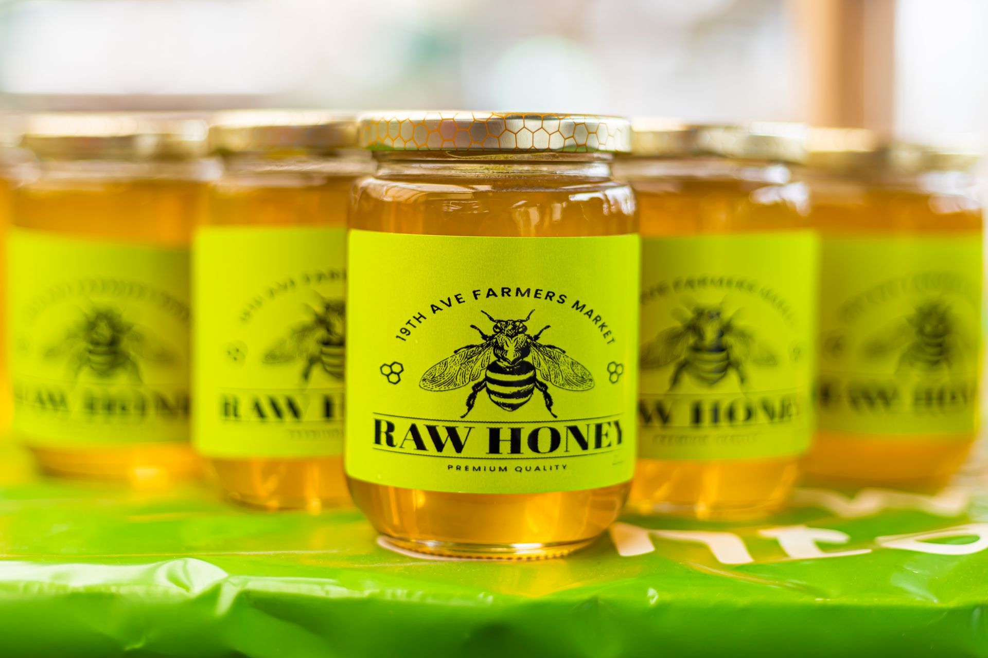 A jar of raw honey is sitting on top of a table next to other jars of honey.