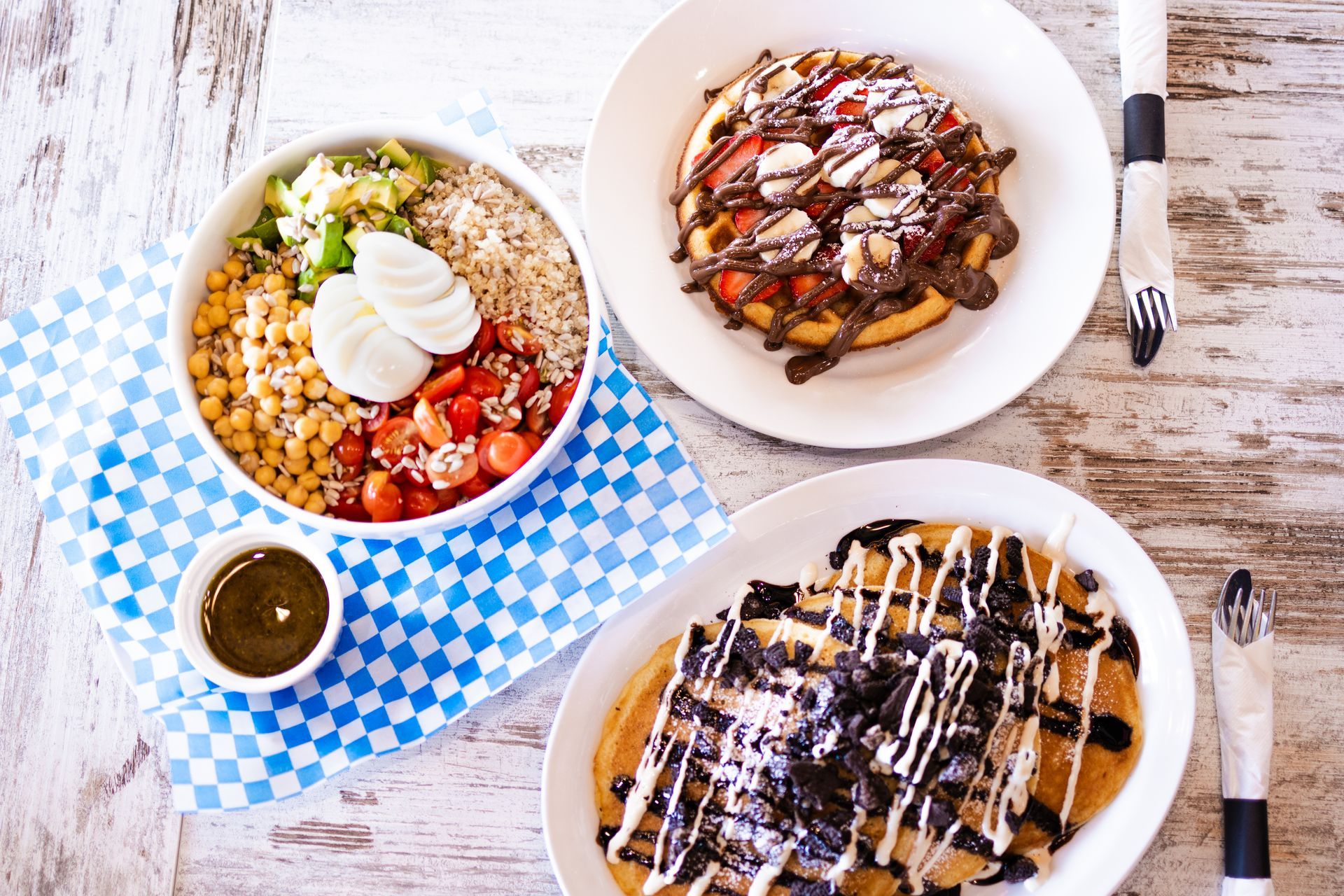 Three plates of food are sitting on a wooden table.
