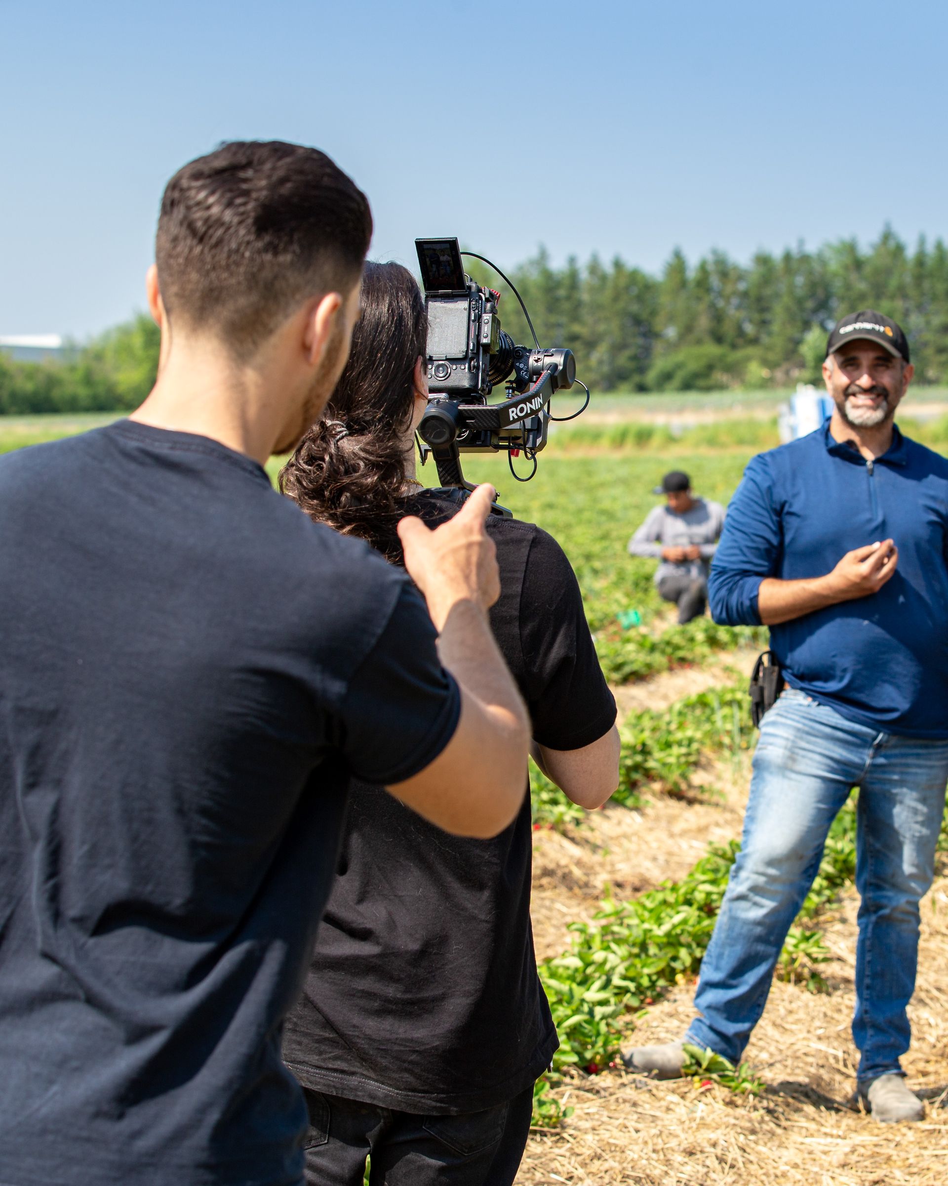 A man is taking a picture of a woman in a field with a camera.
