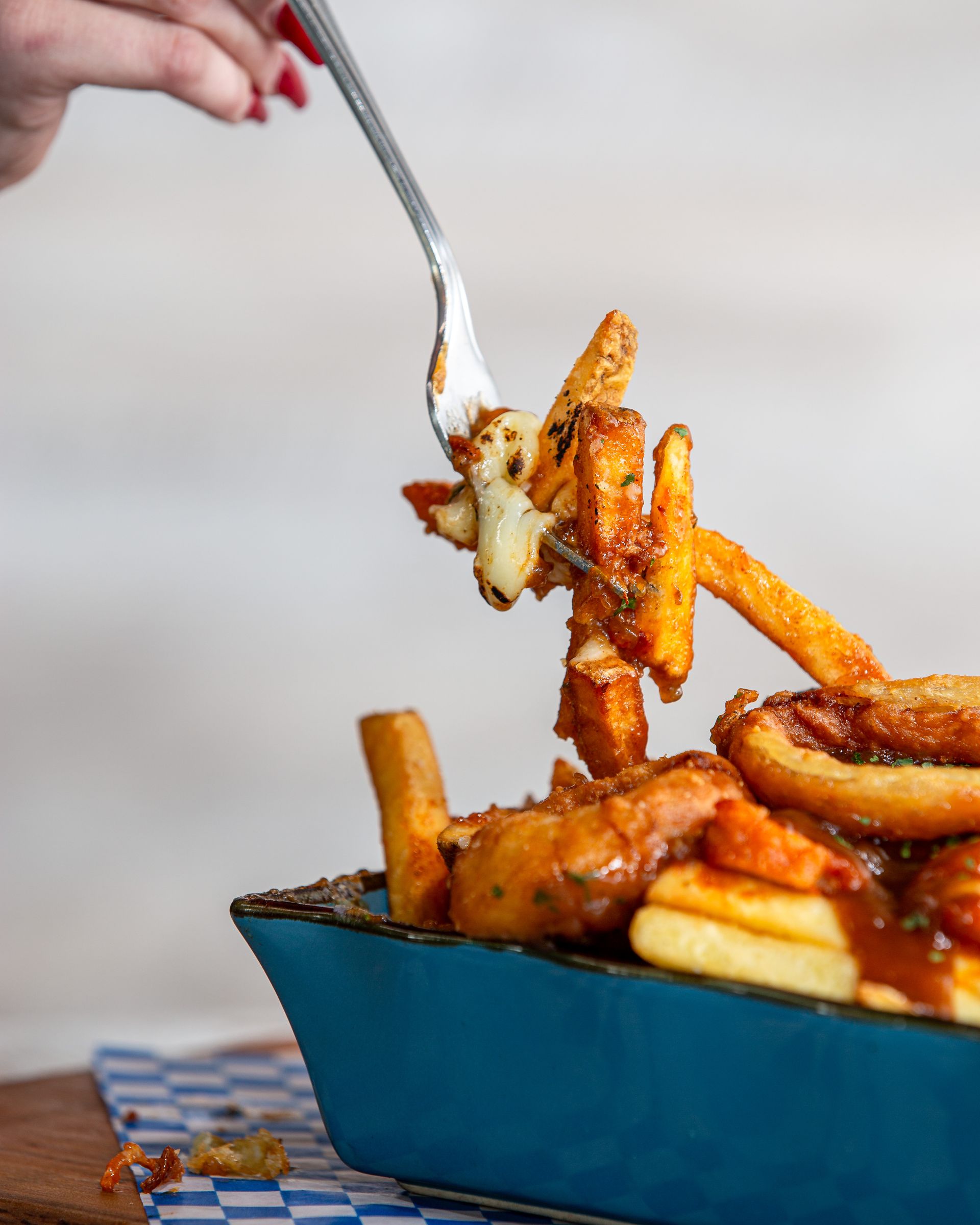 A person is holding a fork over a bowl of french fries