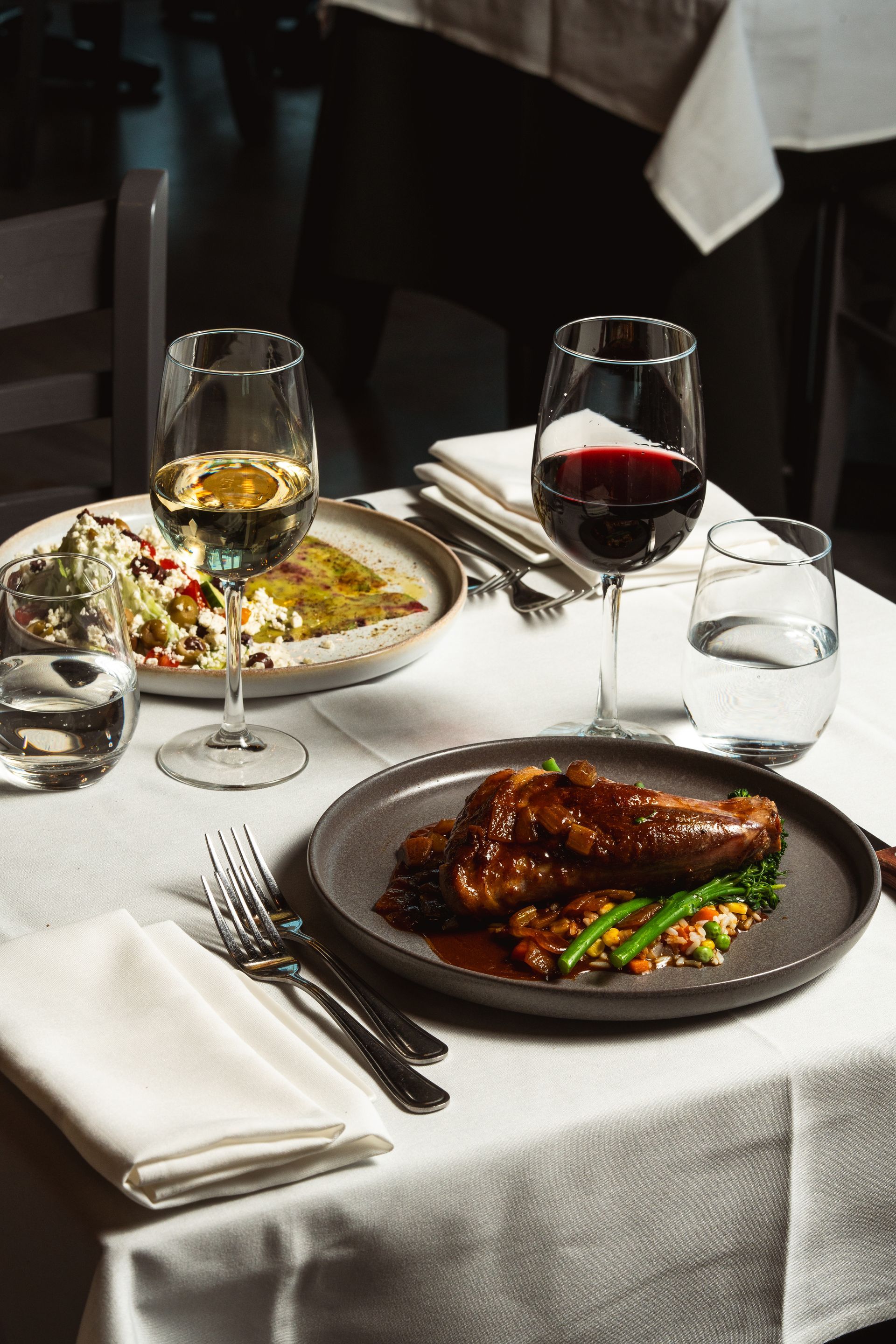 A table with plates of food and glasses of wine on it.