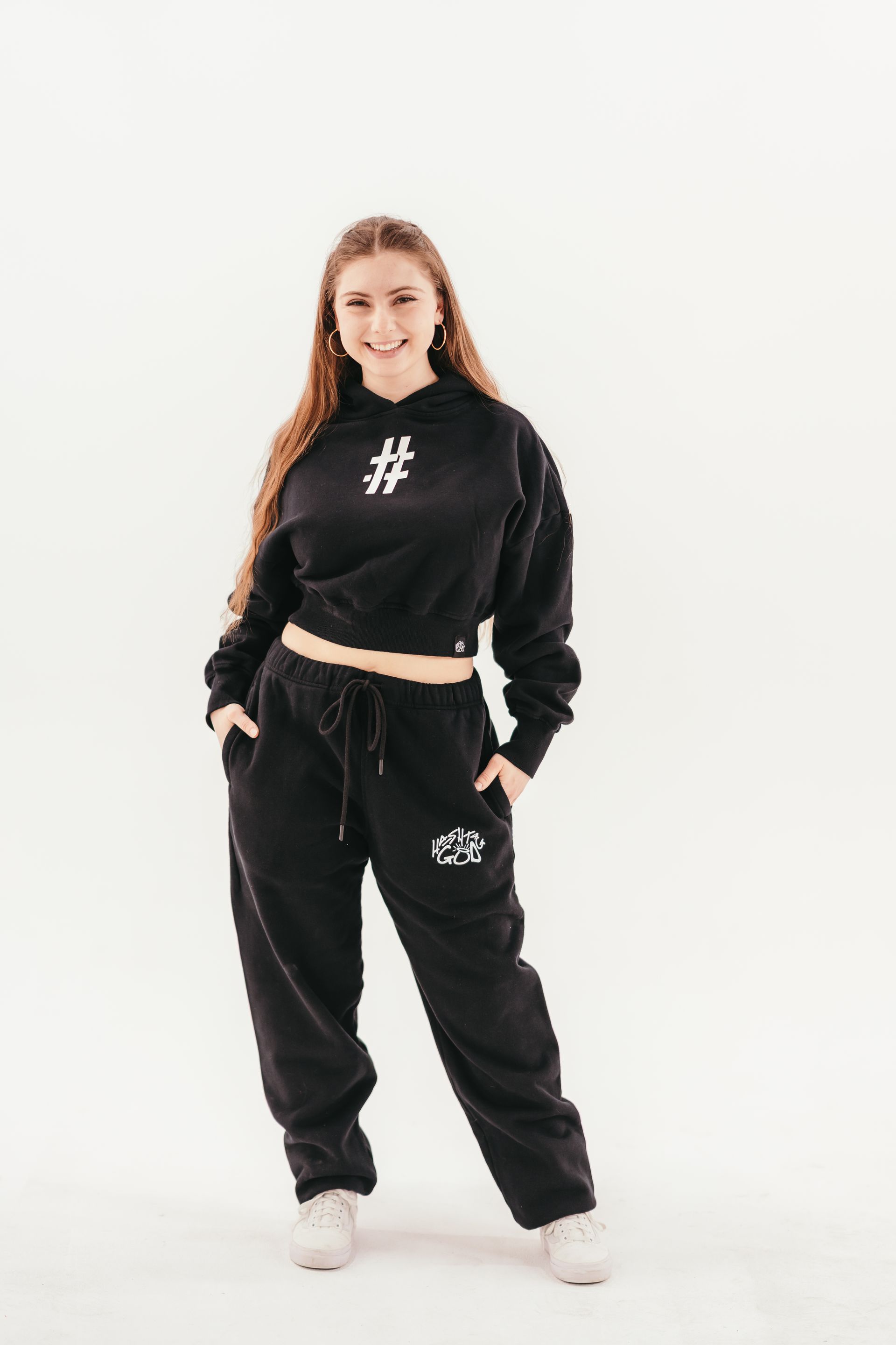 A woman is wearing a black crop top and black sweatpants.