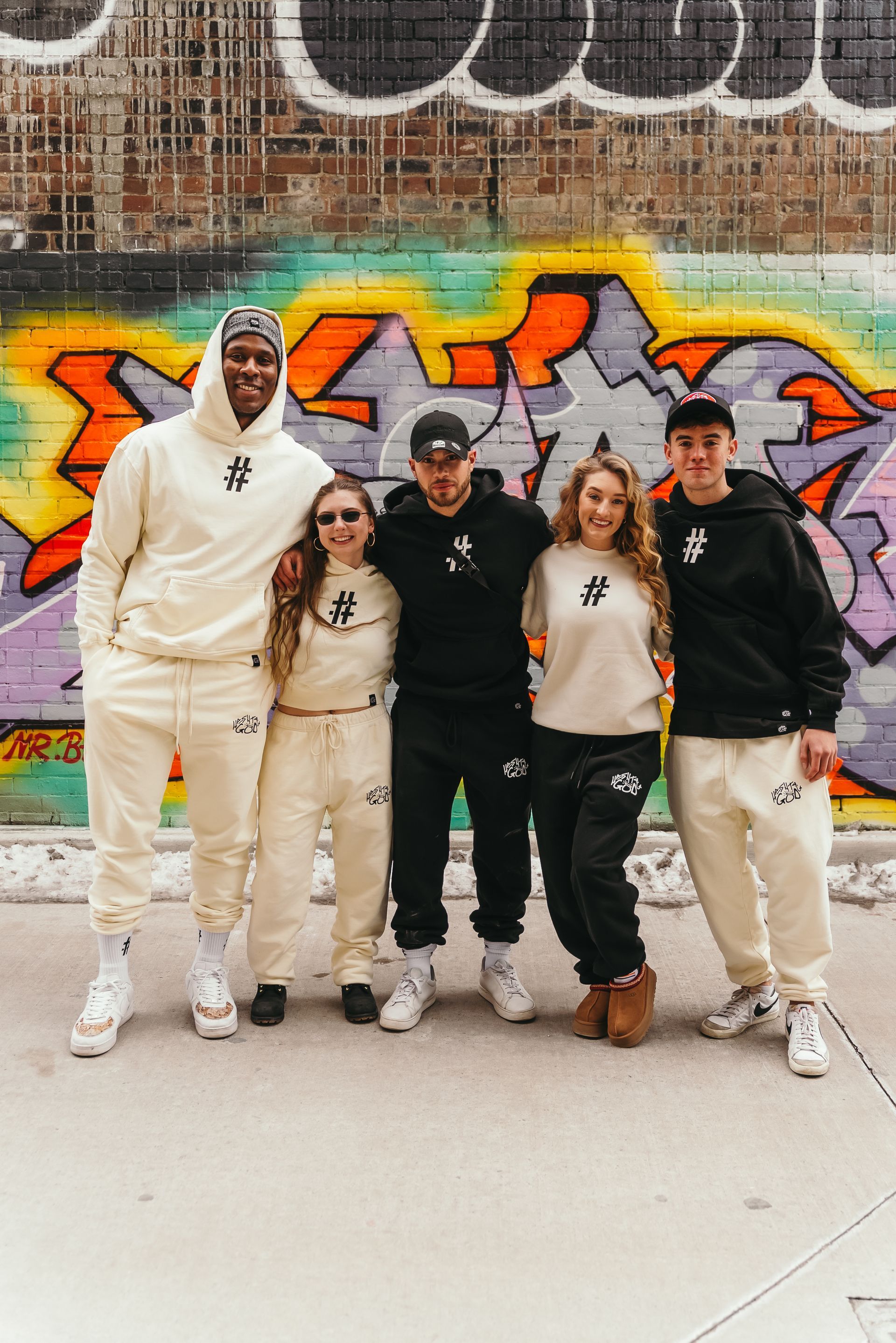 A group of people are posing for a picture in front of a graffiti wall.