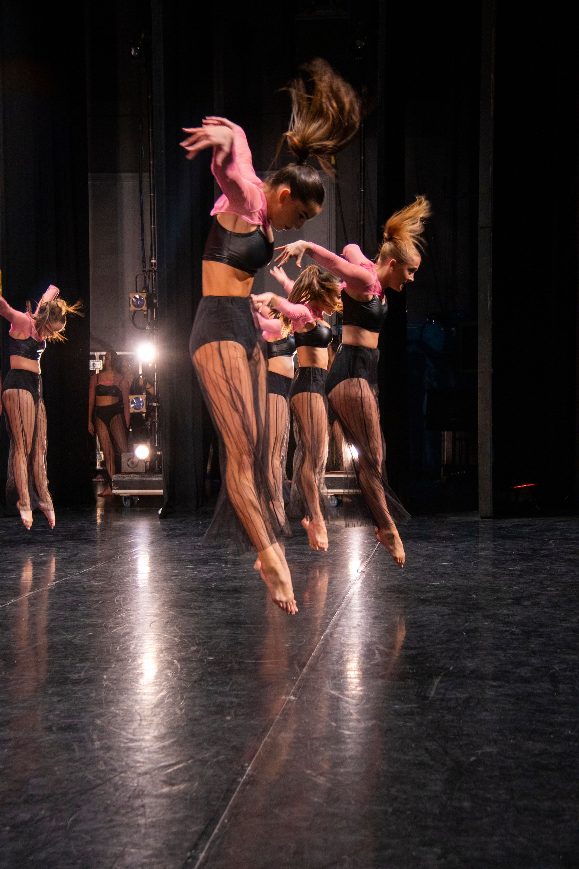 A group of dancers are jumping in the air on a stage.