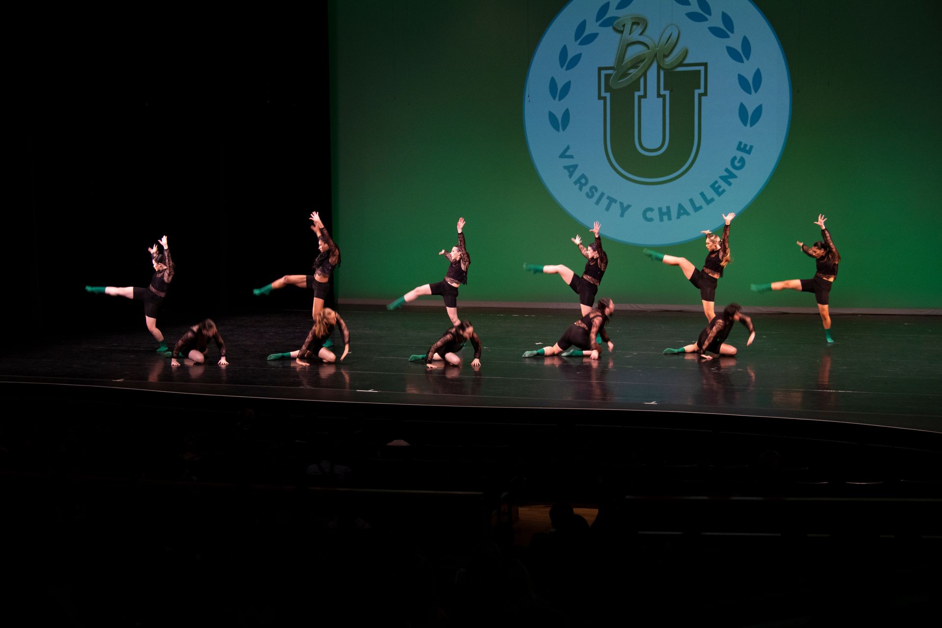 A group of cheerleaders are performing on a stage in front of a varsity challenge logo.