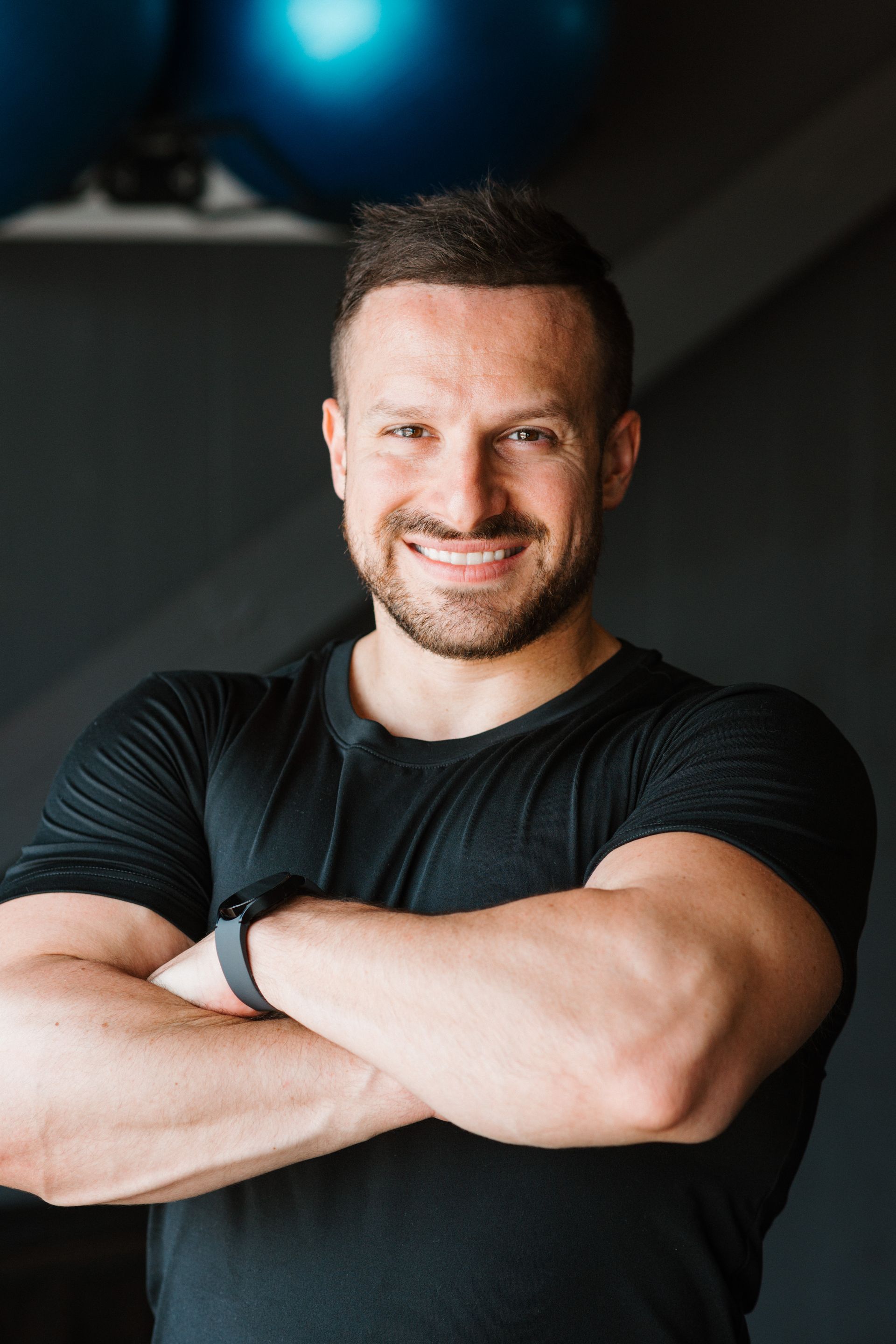 A man with his arms crossed is smiling for the camera in a gym.