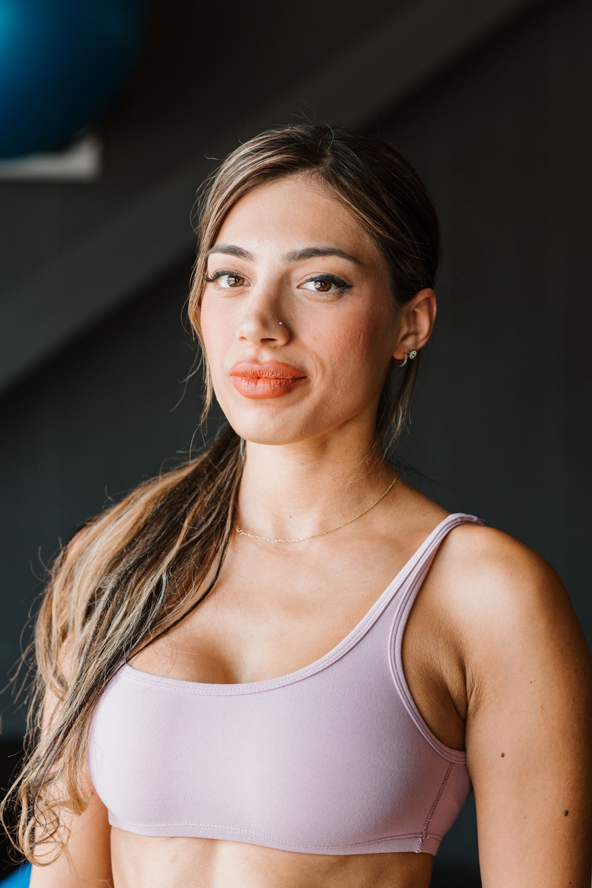 A woman in a purple sports bra is standing in a gym.