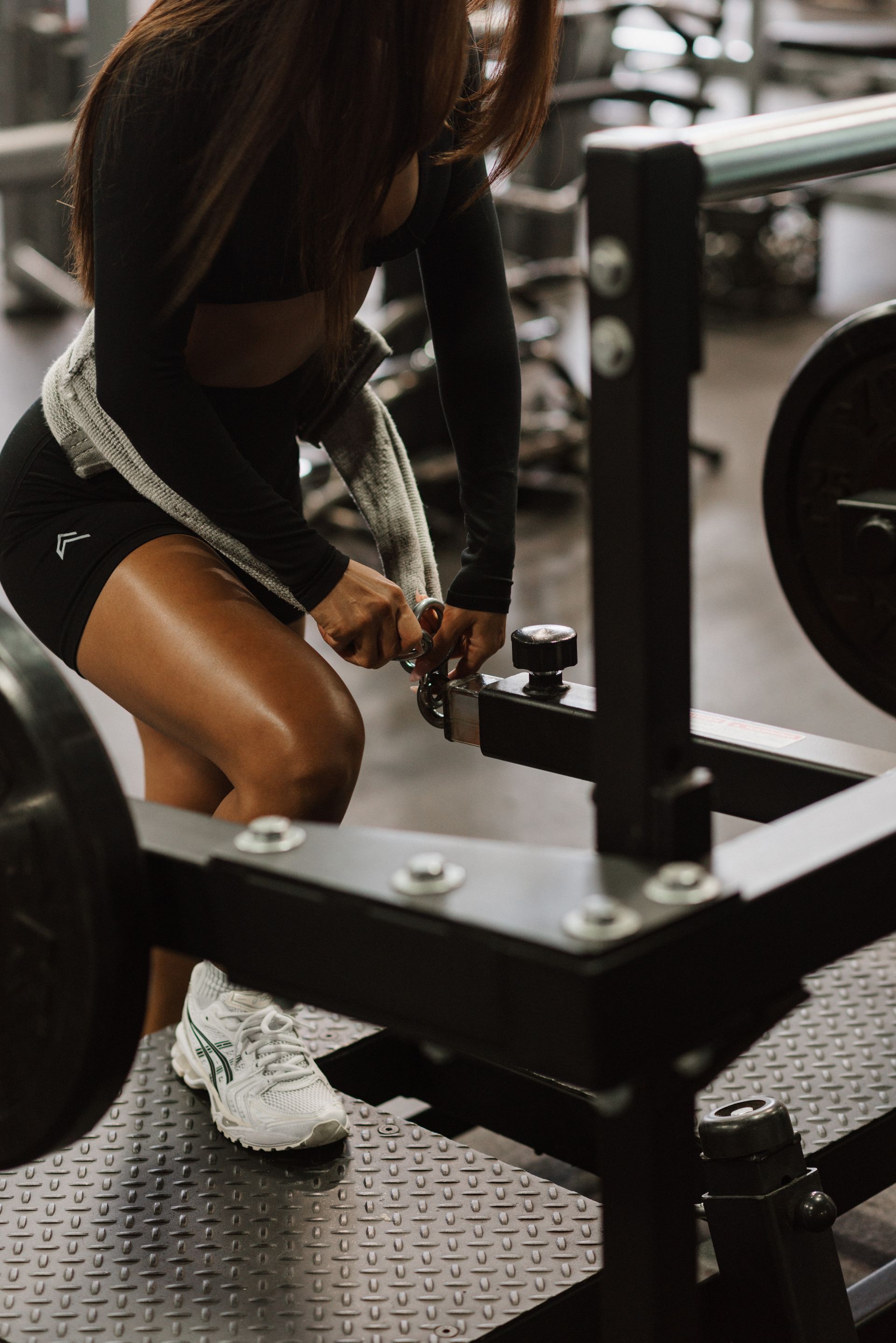 A woman is squatting down with a barbell in a gym.