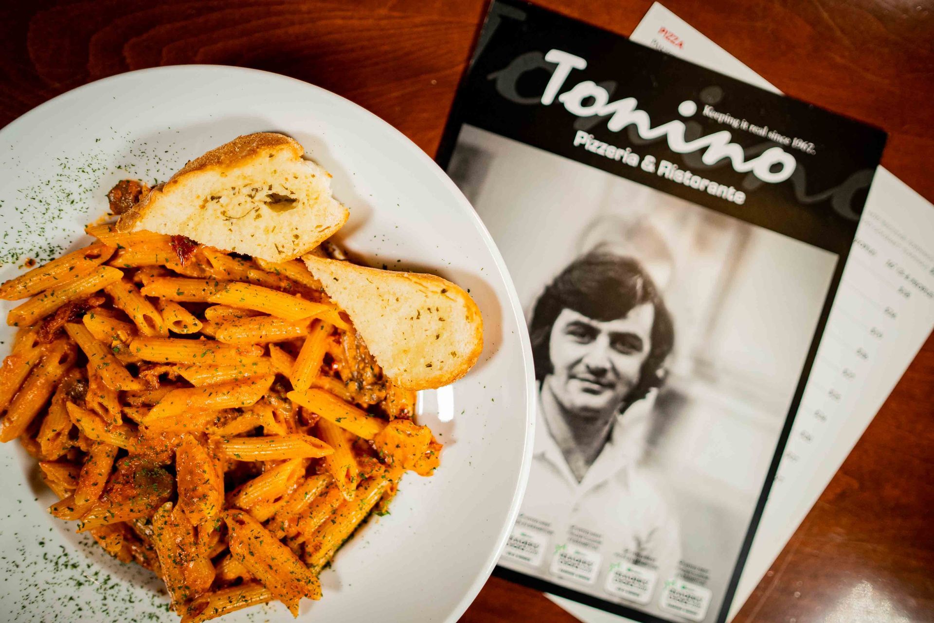 A plate of pasta next to a tonino menu