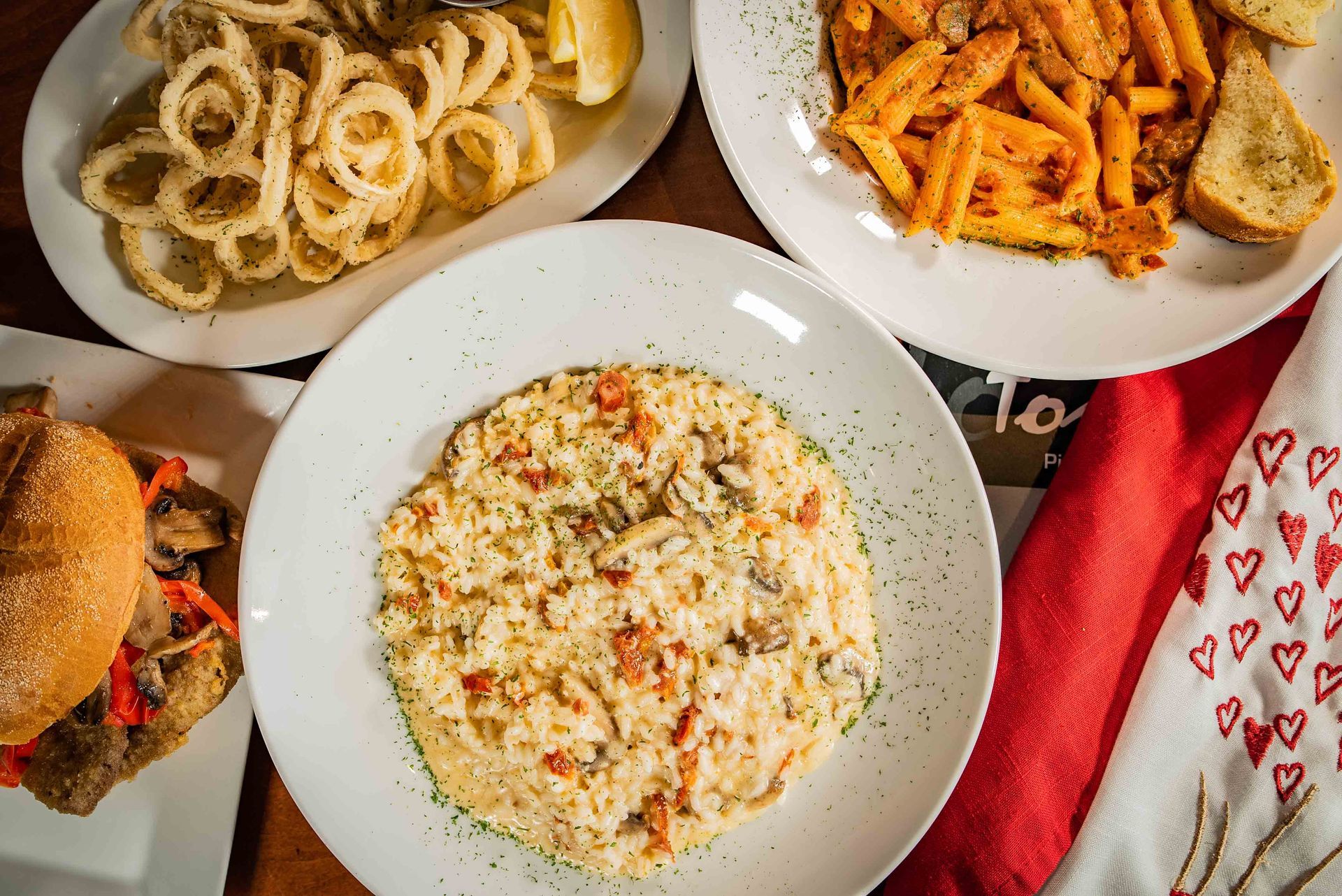A table topped with plates of food and a hamburger.