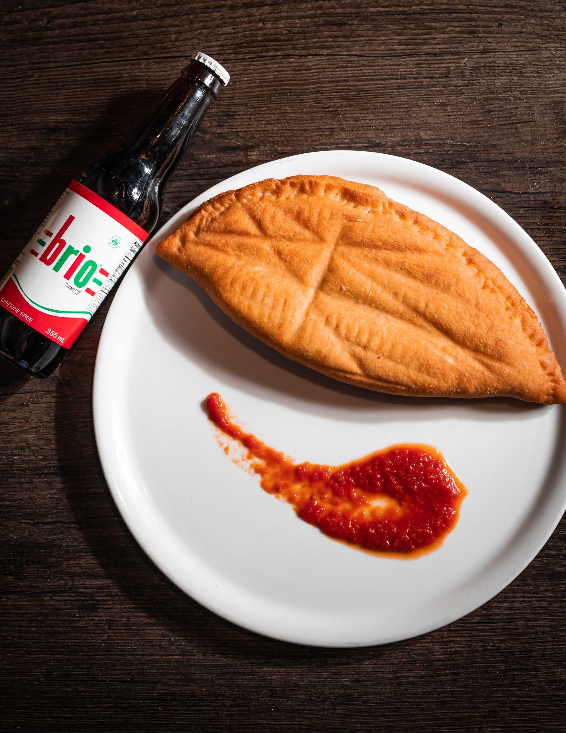 A pizza on a plate next to a bottle of brio