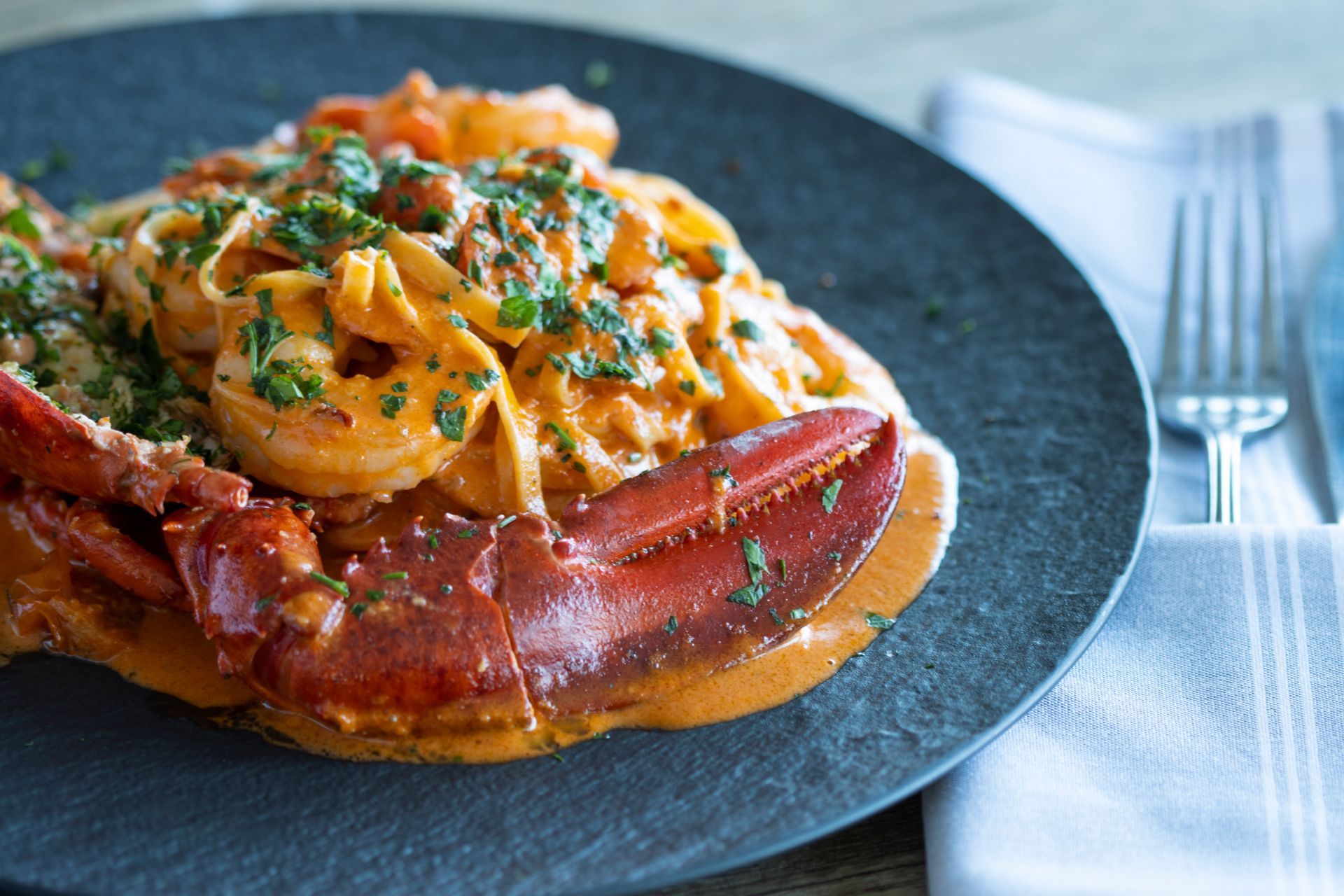 A close up of a plate of food with noodles and lobster on a table.