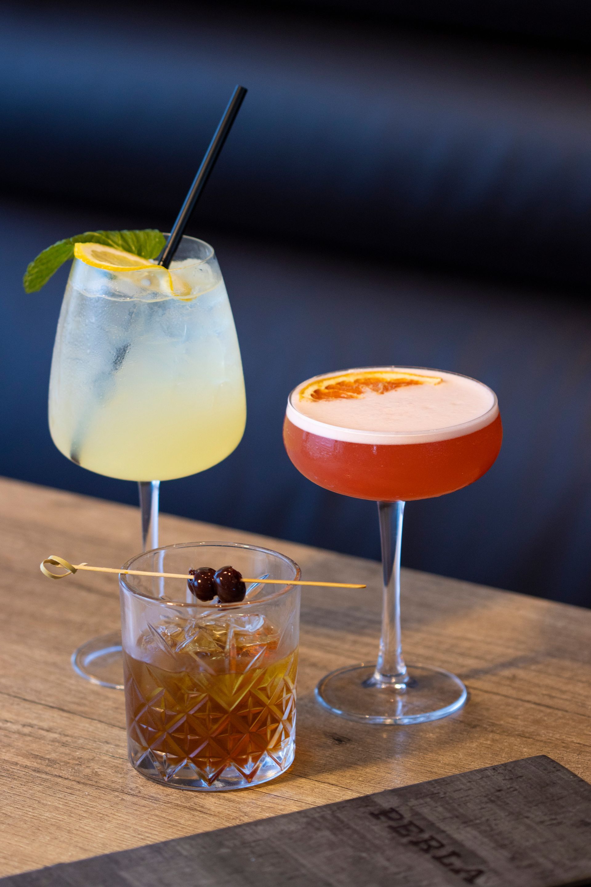 Three different types of cocktails are sitting on a wooden table.
