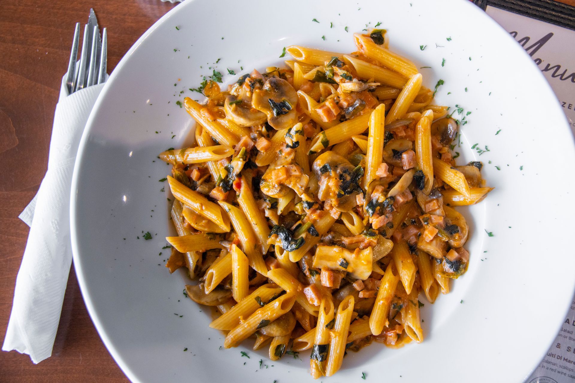 A plate of pasta with a fork and napkin on a table
