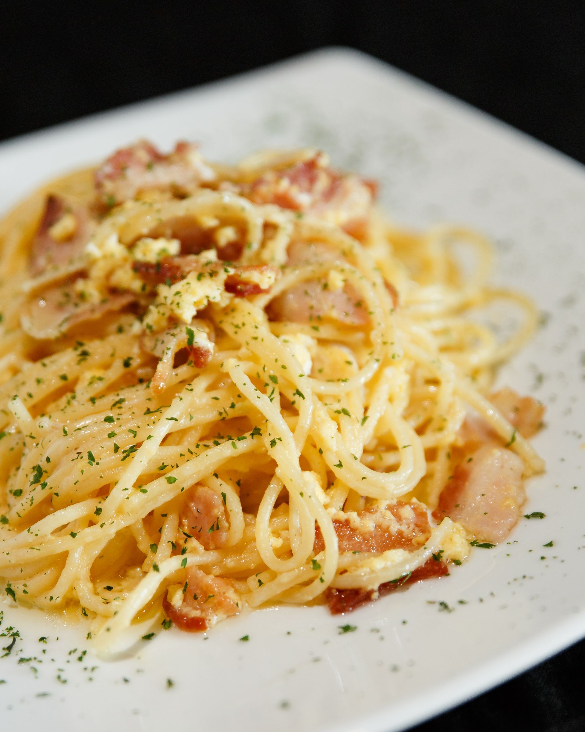 A white plate topped with spaghetti and bacon