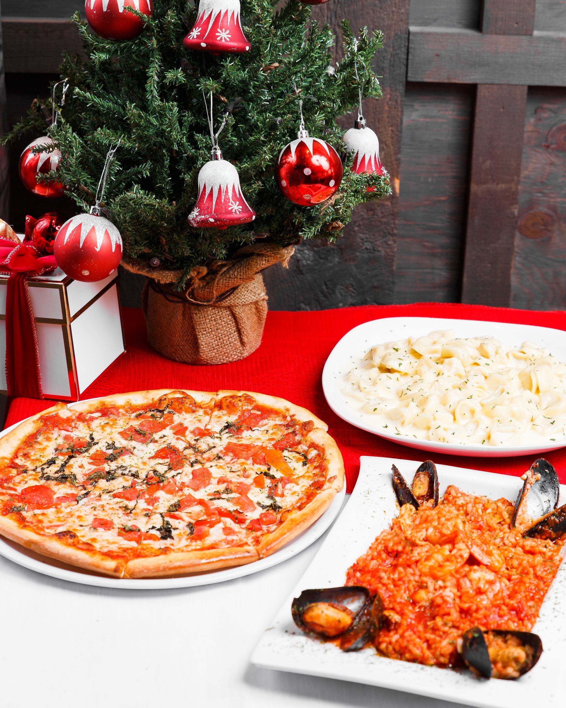 A table with plates of food and a christmas tree in the background