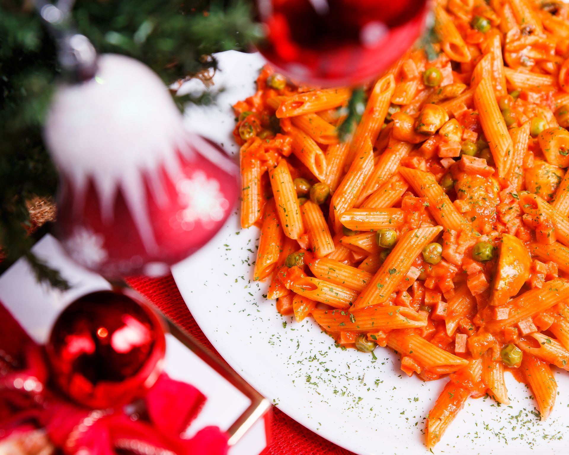 A white plate topped with pasta and vegetables next to a christmas tree
